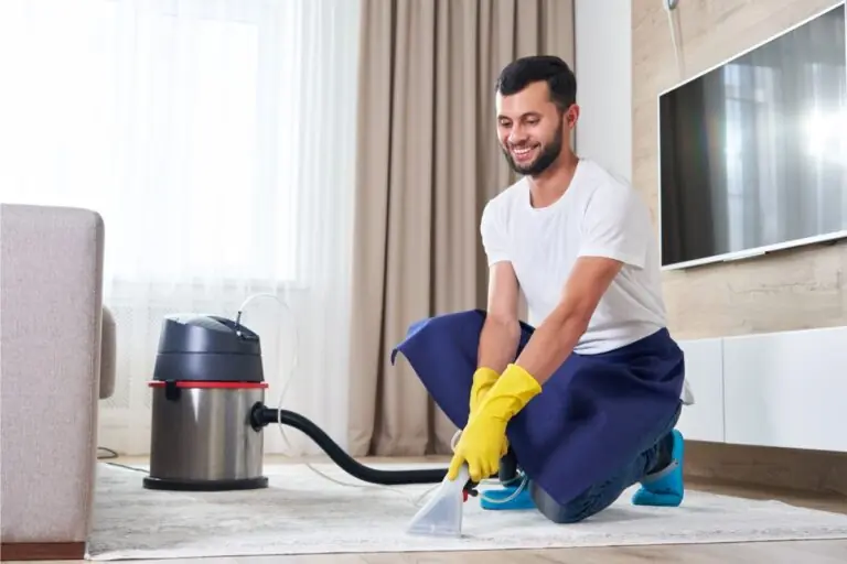 man cleaning carpet in the living room using vacuum cleaner